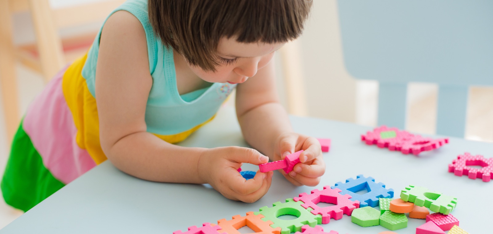 A young child fitting a piece into a wooden puzzle