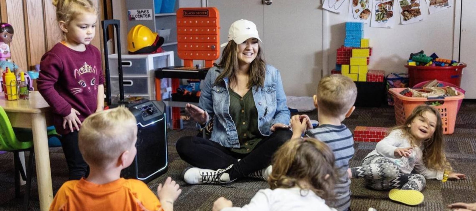 A child care provider sitting on the floor with a circle of toddlers in an Idaho classroom