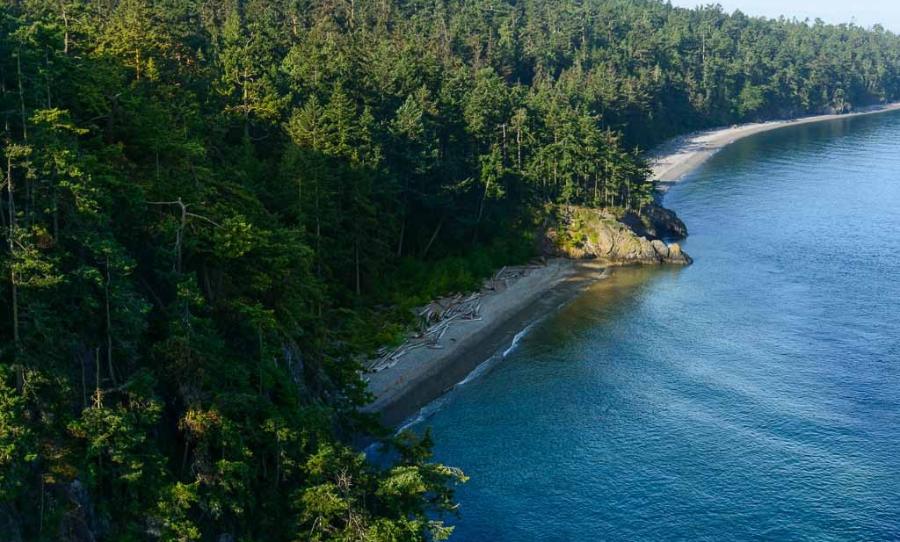 The forested cove and beach inside Deception Pass from above