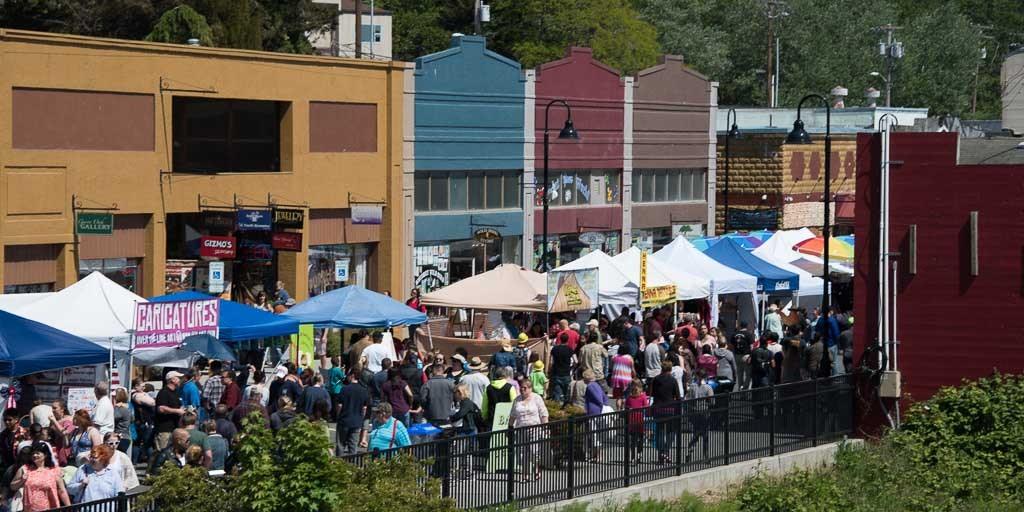Market-day crowds filling Pioneer Way's sidewalks below Oak Harbor's painted storefronts