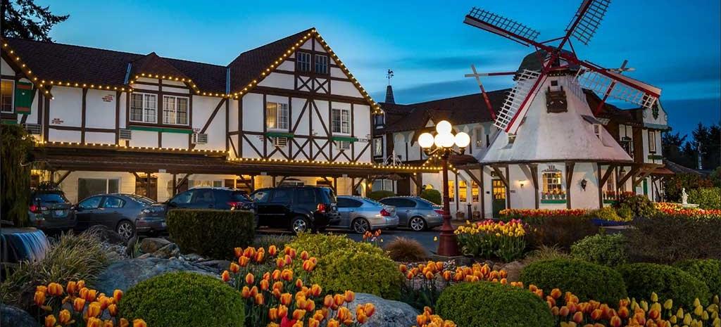 The Auld Holland Inn's windmill lit at dusk over beds of red and orange tulips