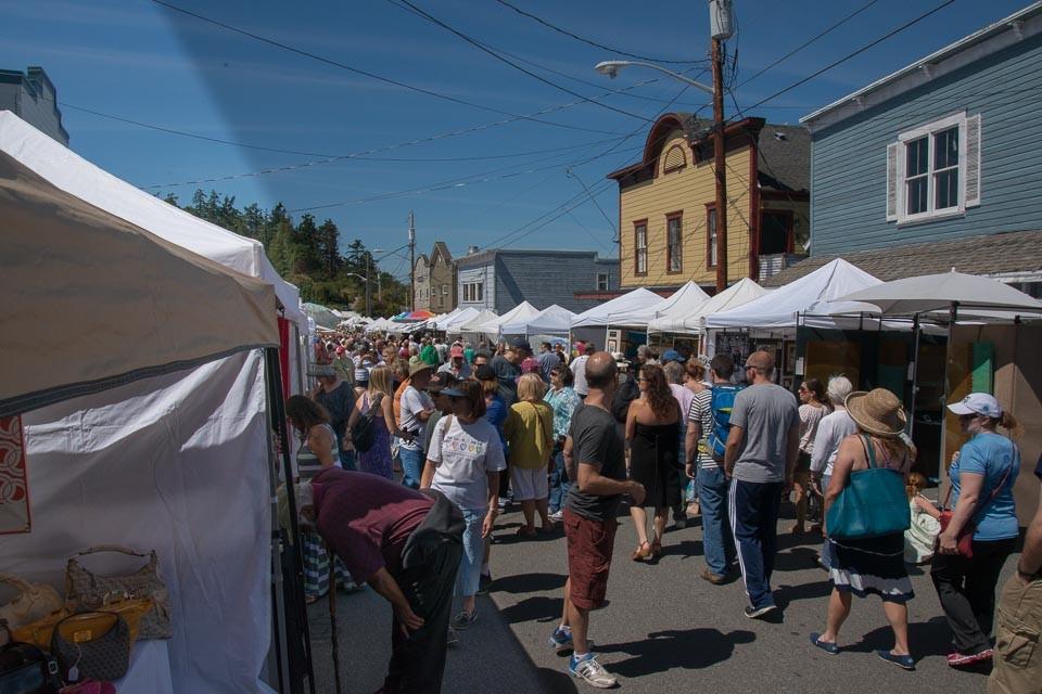 Festival crowds moving between white booth tents on Coupeville's main street