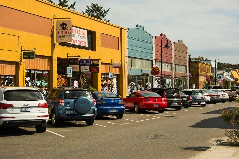 Oak Harbor's Pioneer Way storefronts painted in reds, yellows and blues on a clear afternoon