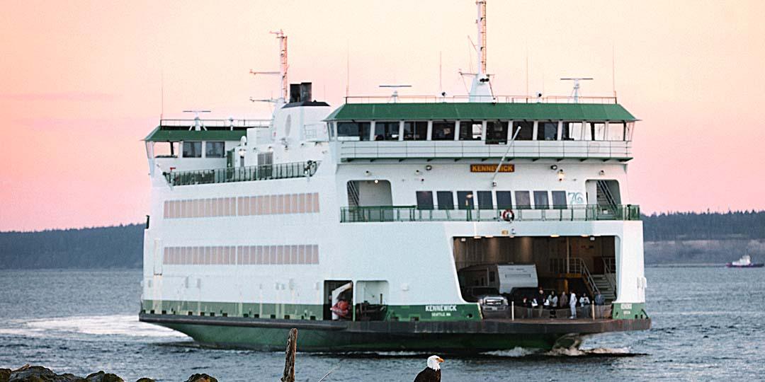 A ferry mid-crossing at dawn with walk-on passengers on deck, sky and water washed rose and grey