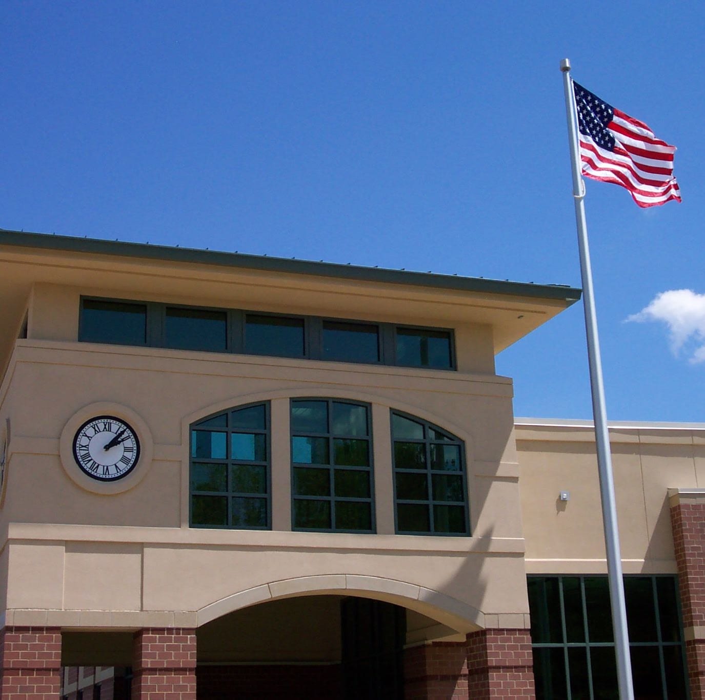 The Arnold Branch: tan stucco and brick with an arched entry, flag, and clock tower under an open sky