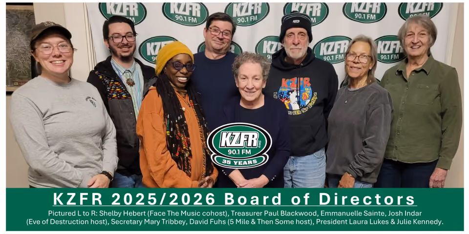 Group photo of eight KZFR 2025/2026 Board of Directors members standing together in front of a KZFR 90.1 FM banner