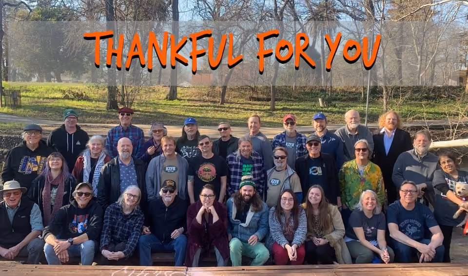 Group photo of about 30 KZFR volunteers posing outdoors in three rows, with orange text reading "Thankful For You" across the top