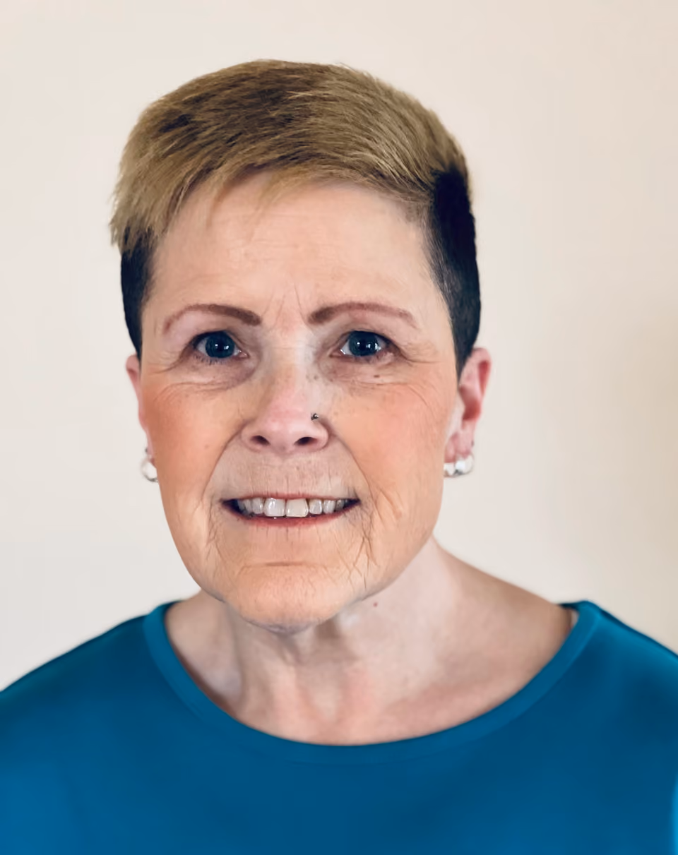 Headshot of a smiling woman with short blond hair and a teal top, one of the committee members featured in the post