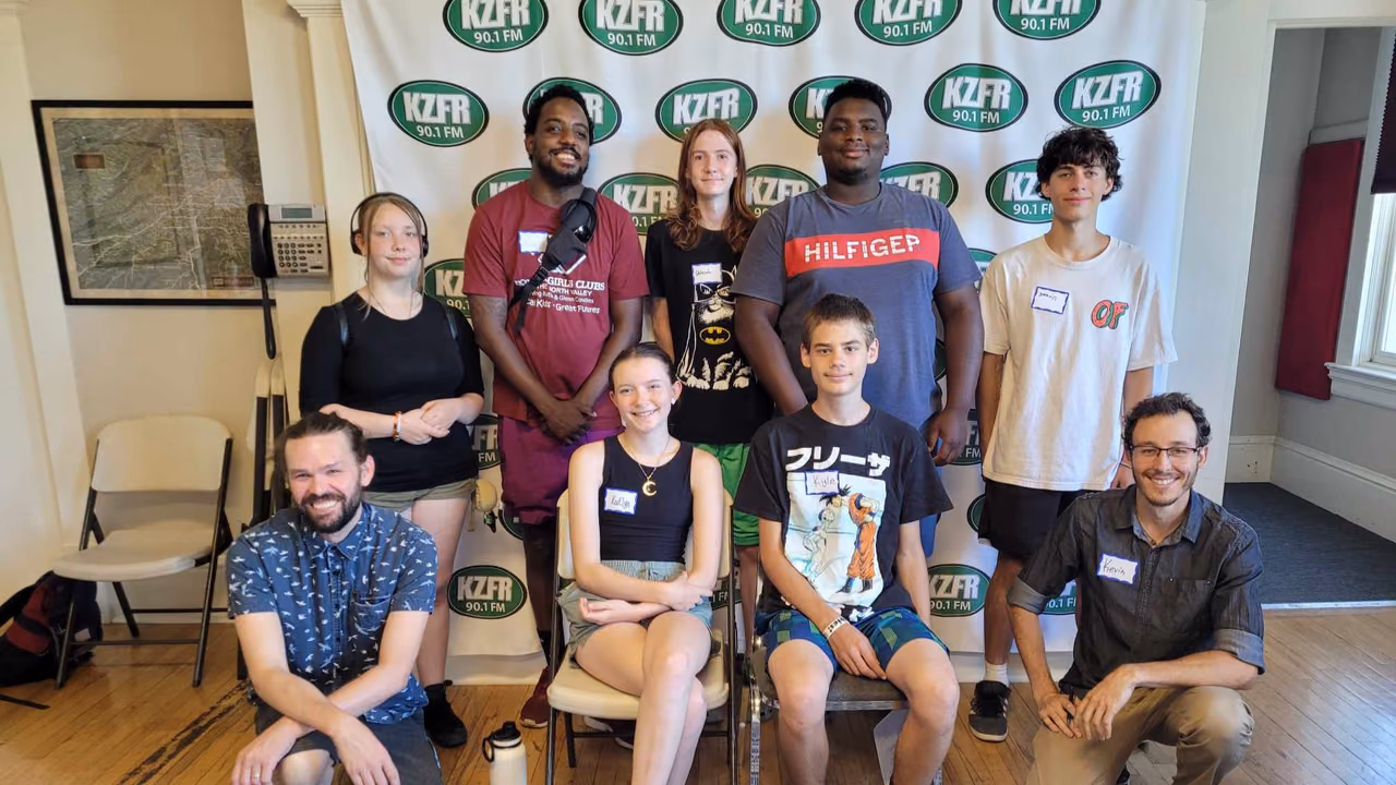 Youth from the Boys & Girls Club of the North Valley with KZFR staff in front of the station backdrop.