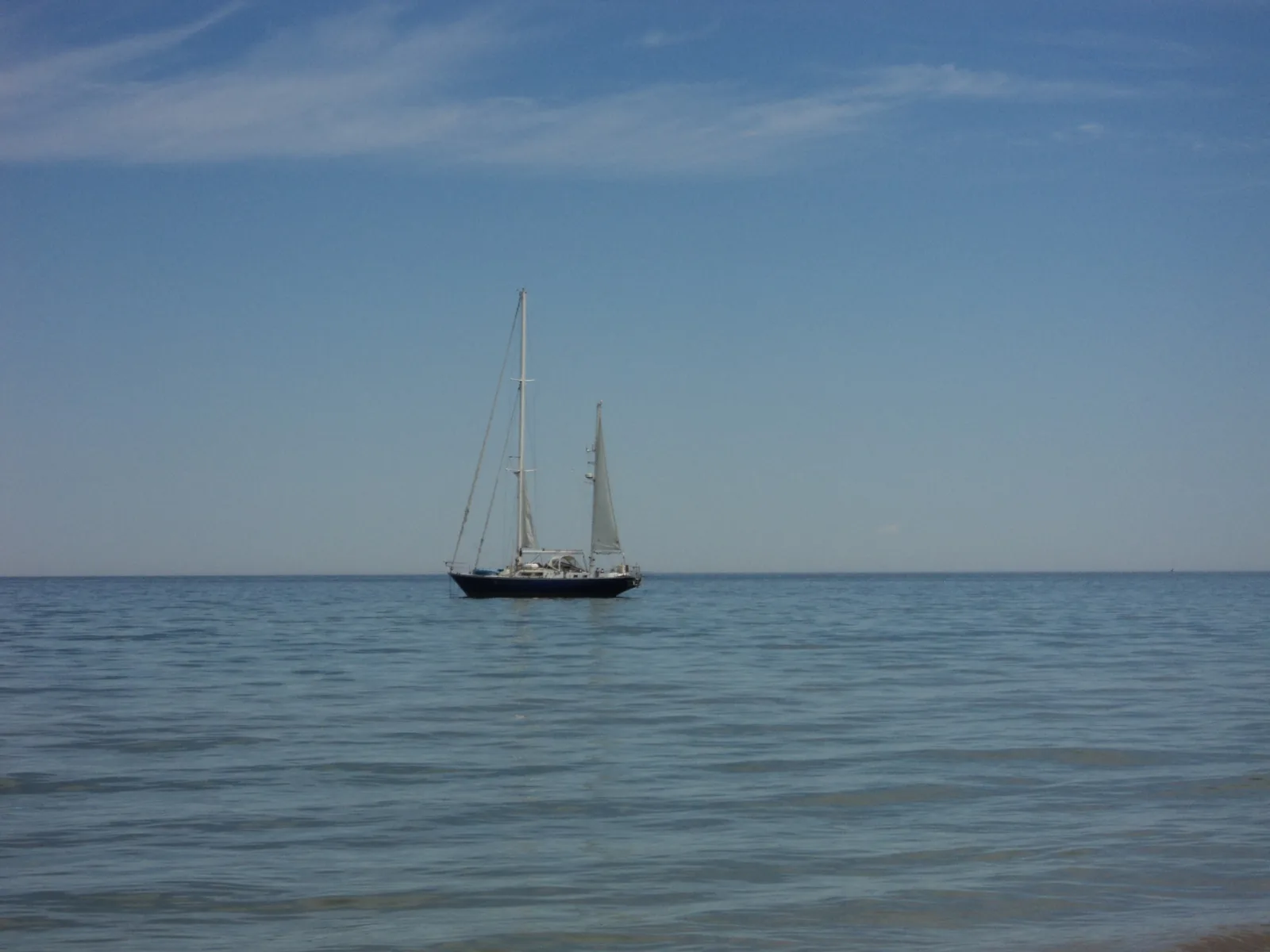 A sailboat on Lake Michigan seen from the public beach in Leland