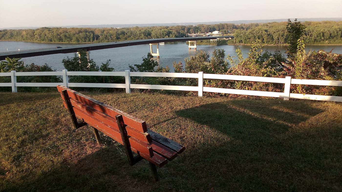 A park bench and picket fence overlooking the Mississippi River at Riverview Park.