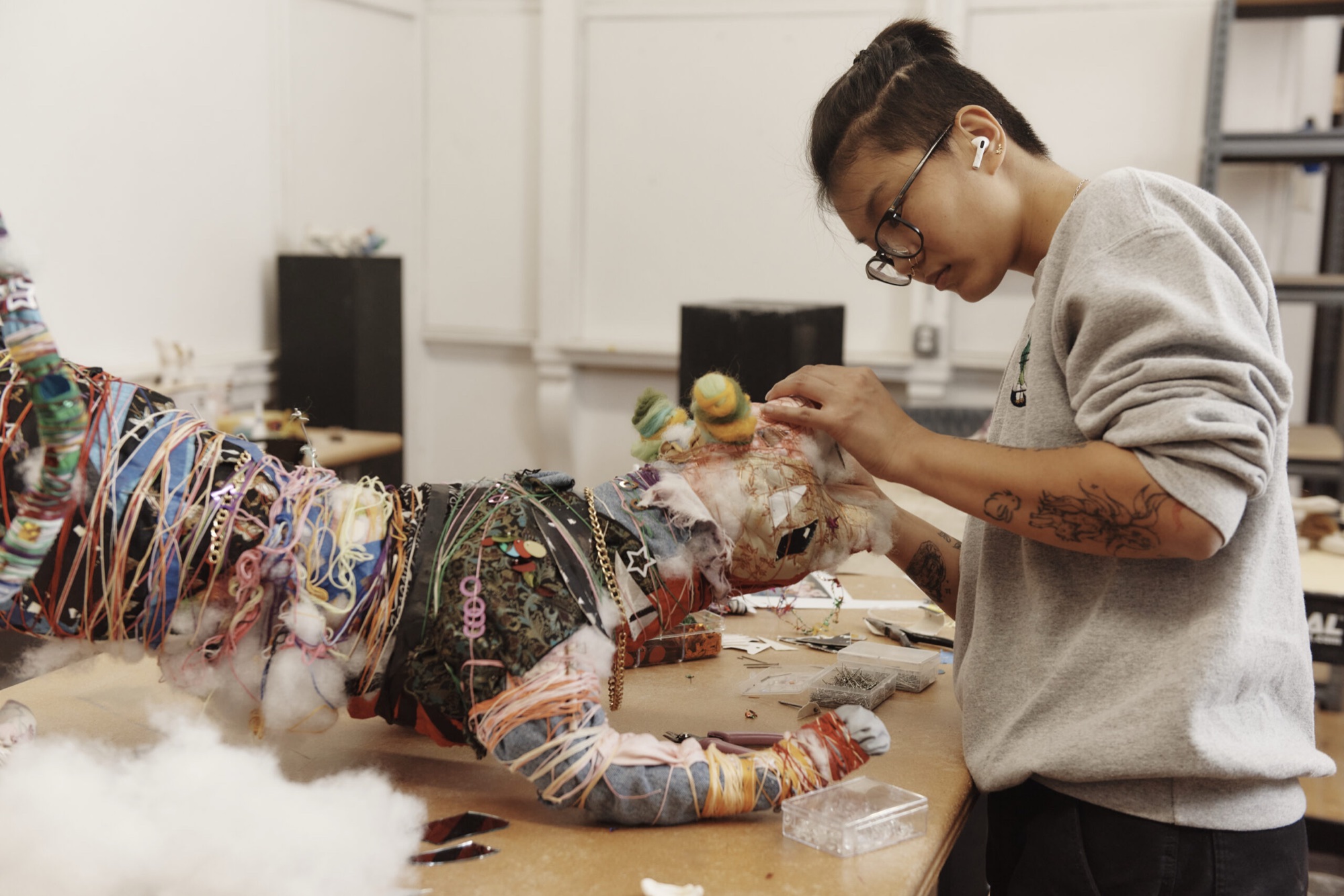 A MassArt student works on a sculpture at a studio table.