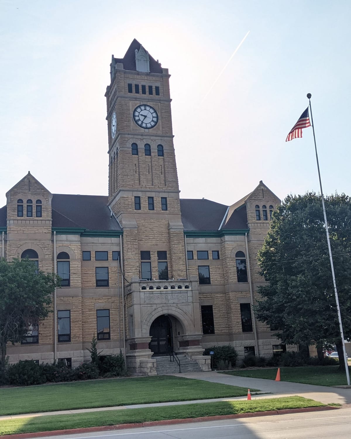 The Mitchell County Courthouse in Beloit, native limestone with its clock and bell tower, under a blue sky