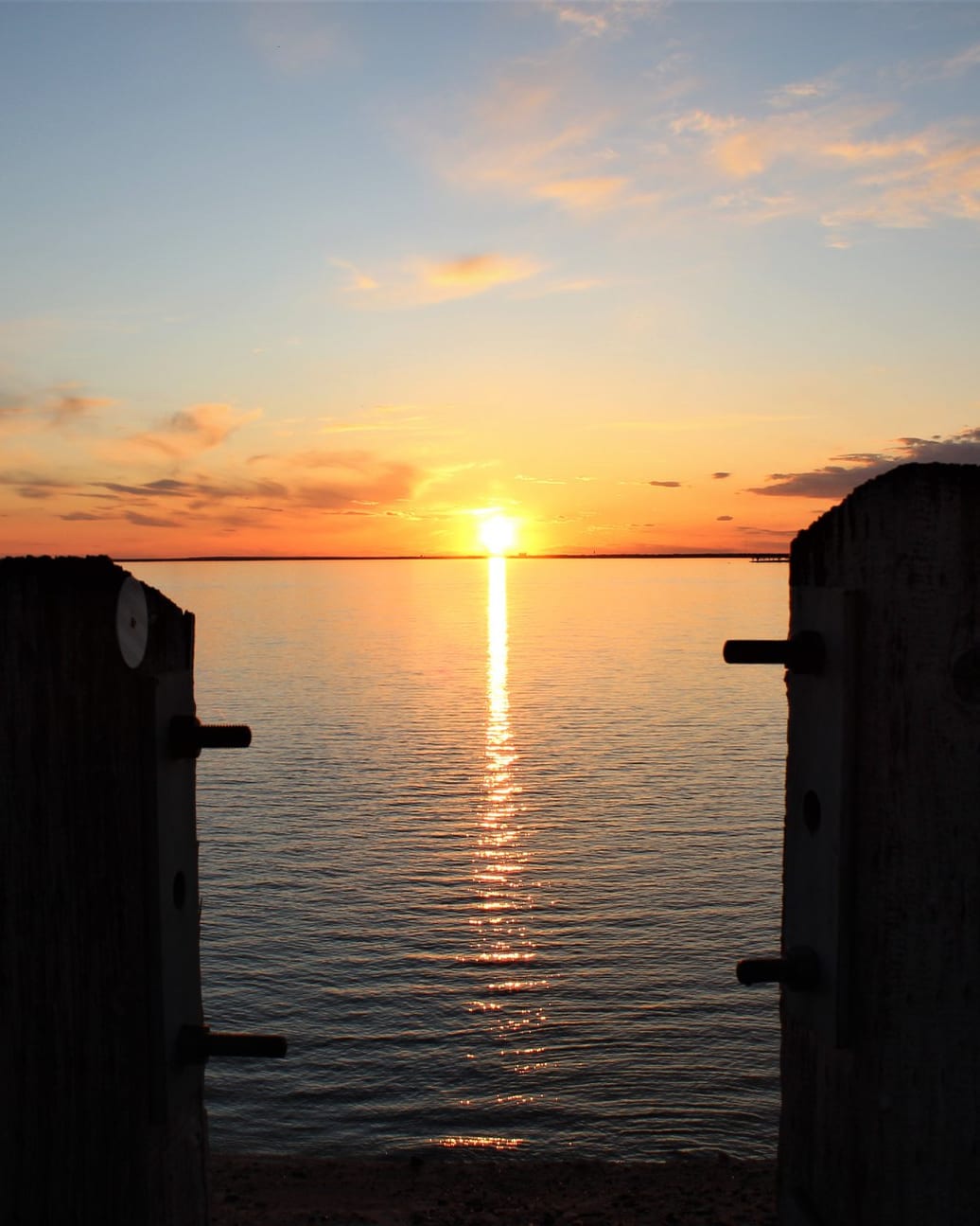 Sunset over Waconda Lake from a dock, the sun a line of light on the water