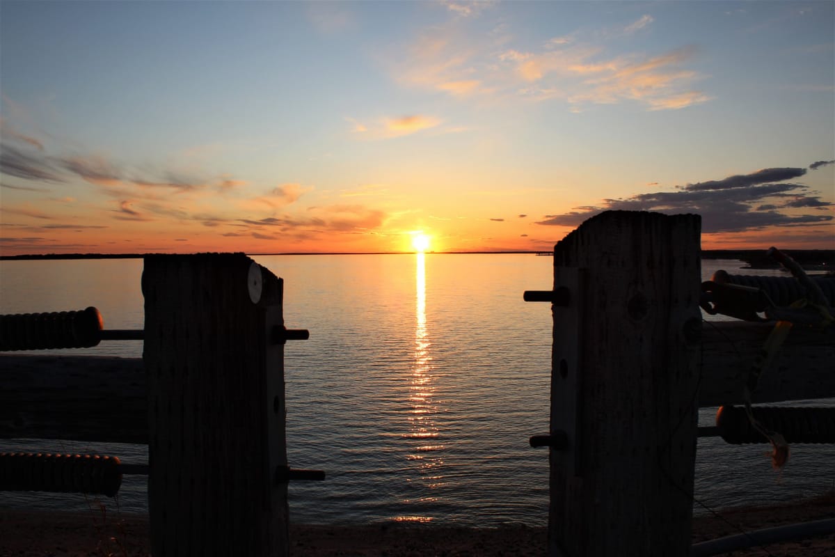Sunset over Waconda Lake from a dock, the sun a line of light on the water
