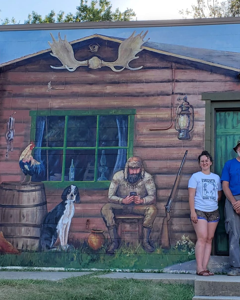 A group in front of the green Trapper Lodge building in Simpson
