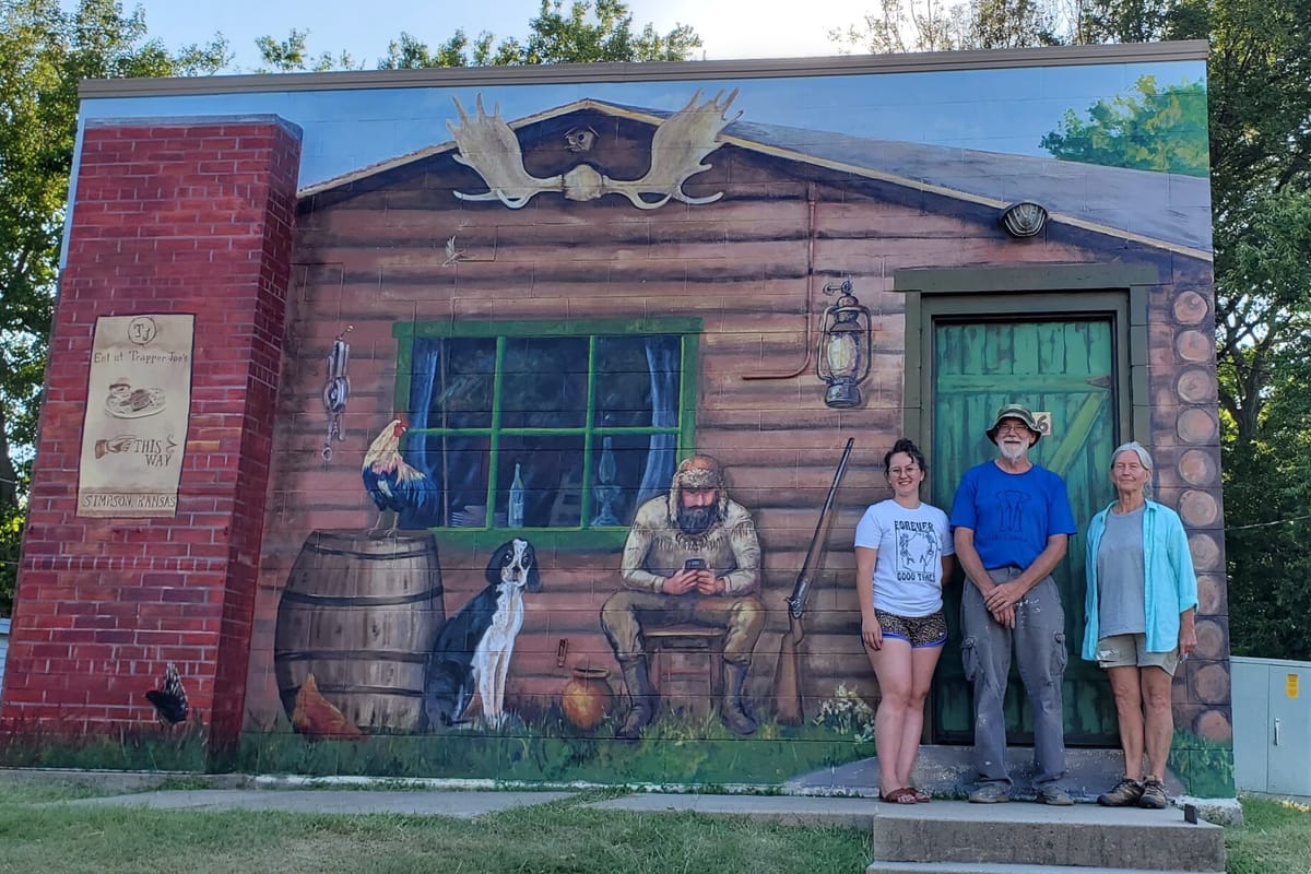 A group in front of the green Trapper Lodge building in Simpson