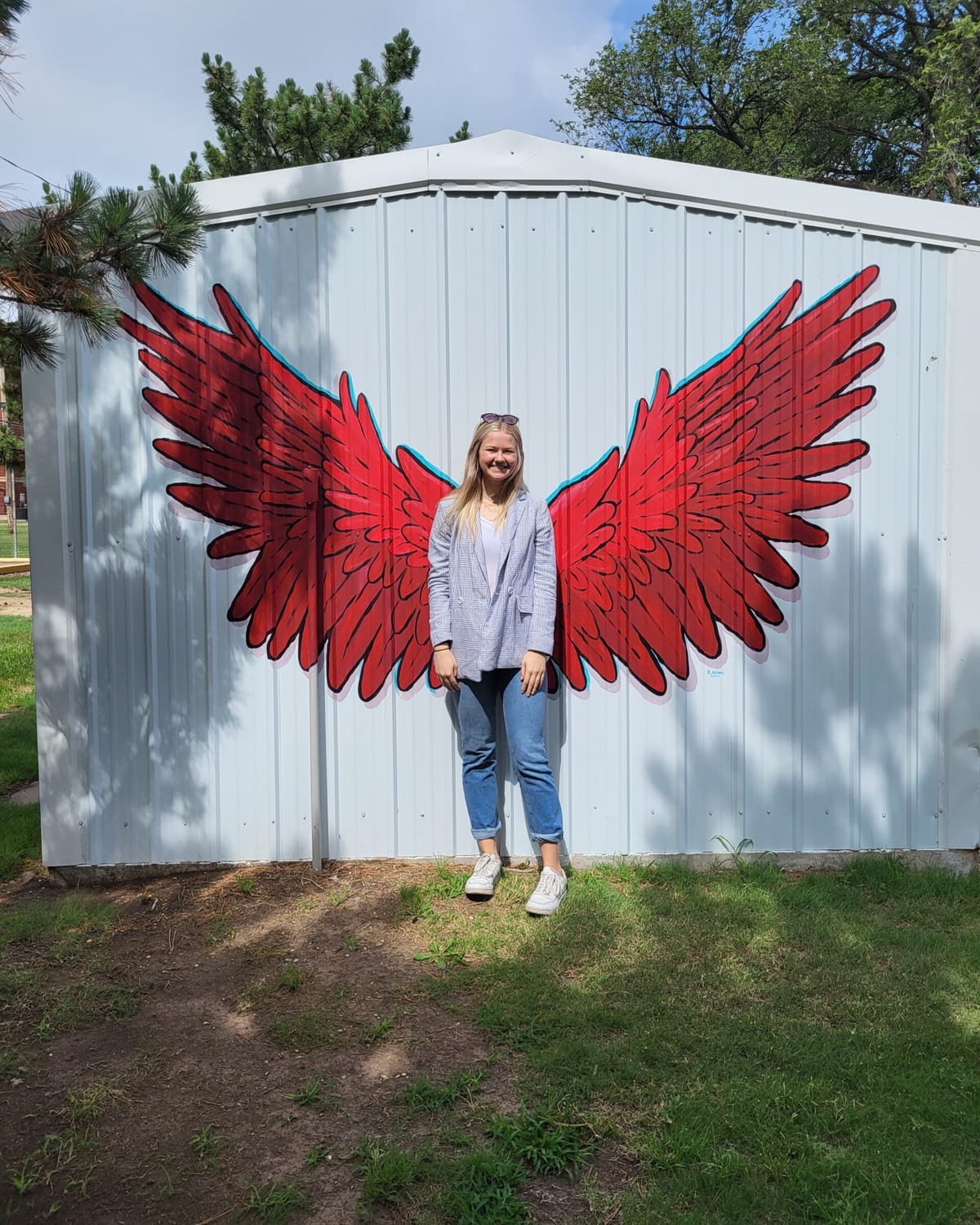 A woman standing in front of the red wings mural in Tipton