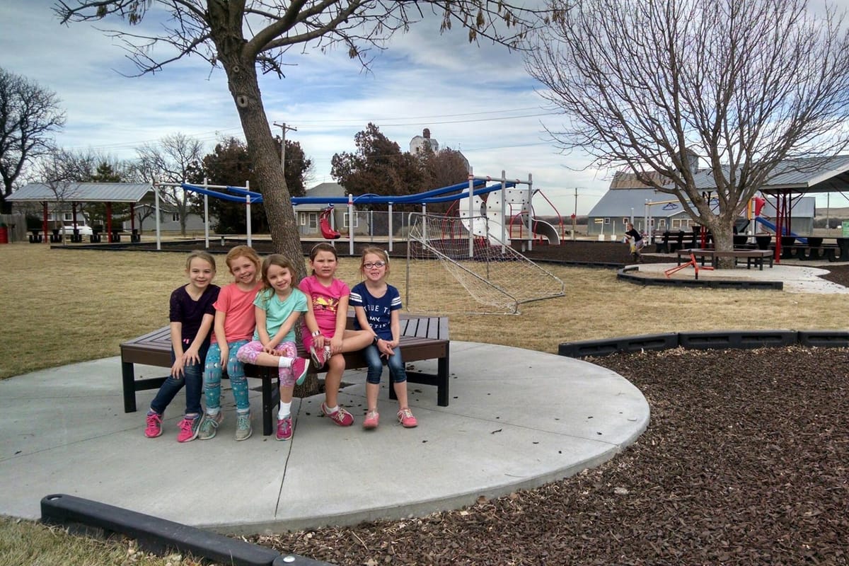 A family on a bench on the plaza at Tipton City Park