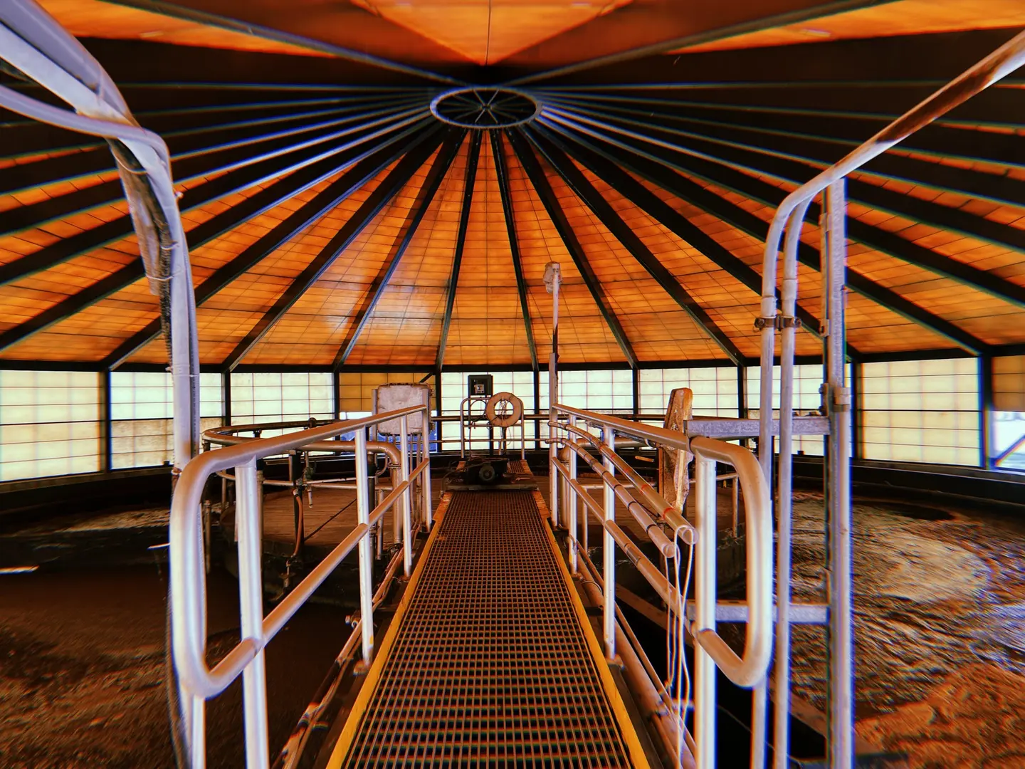 A railed walkway crossing a covered clarifier under a radial wooden dome