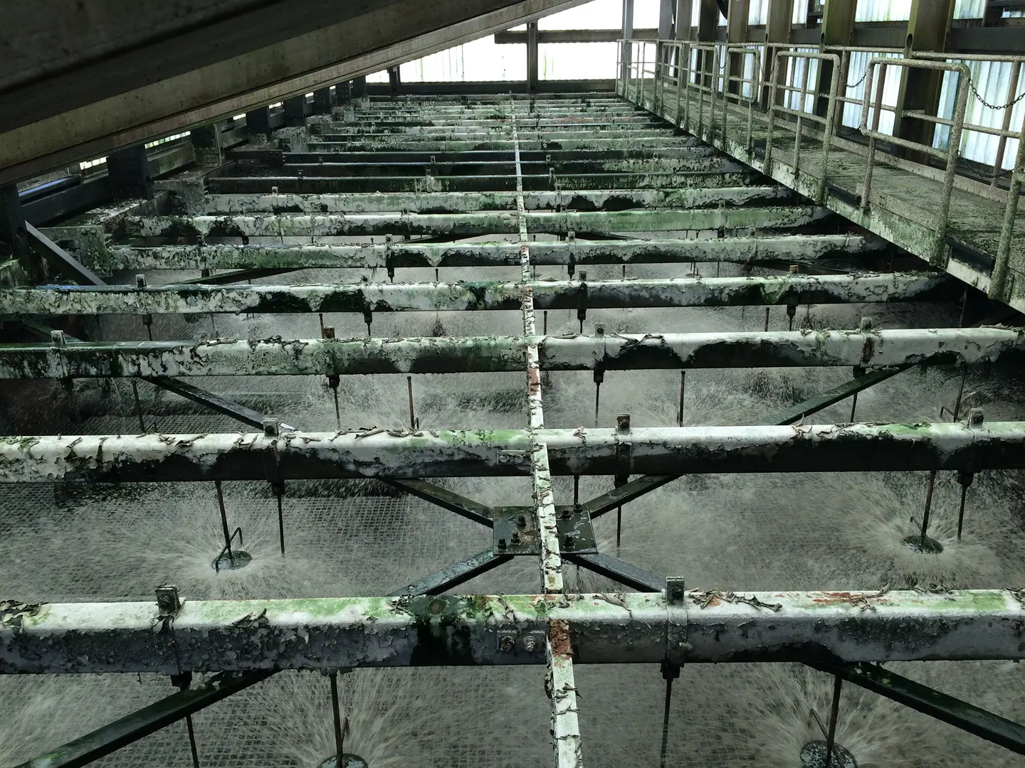 Rows of metal scrapers over long treatment channels inside a plant