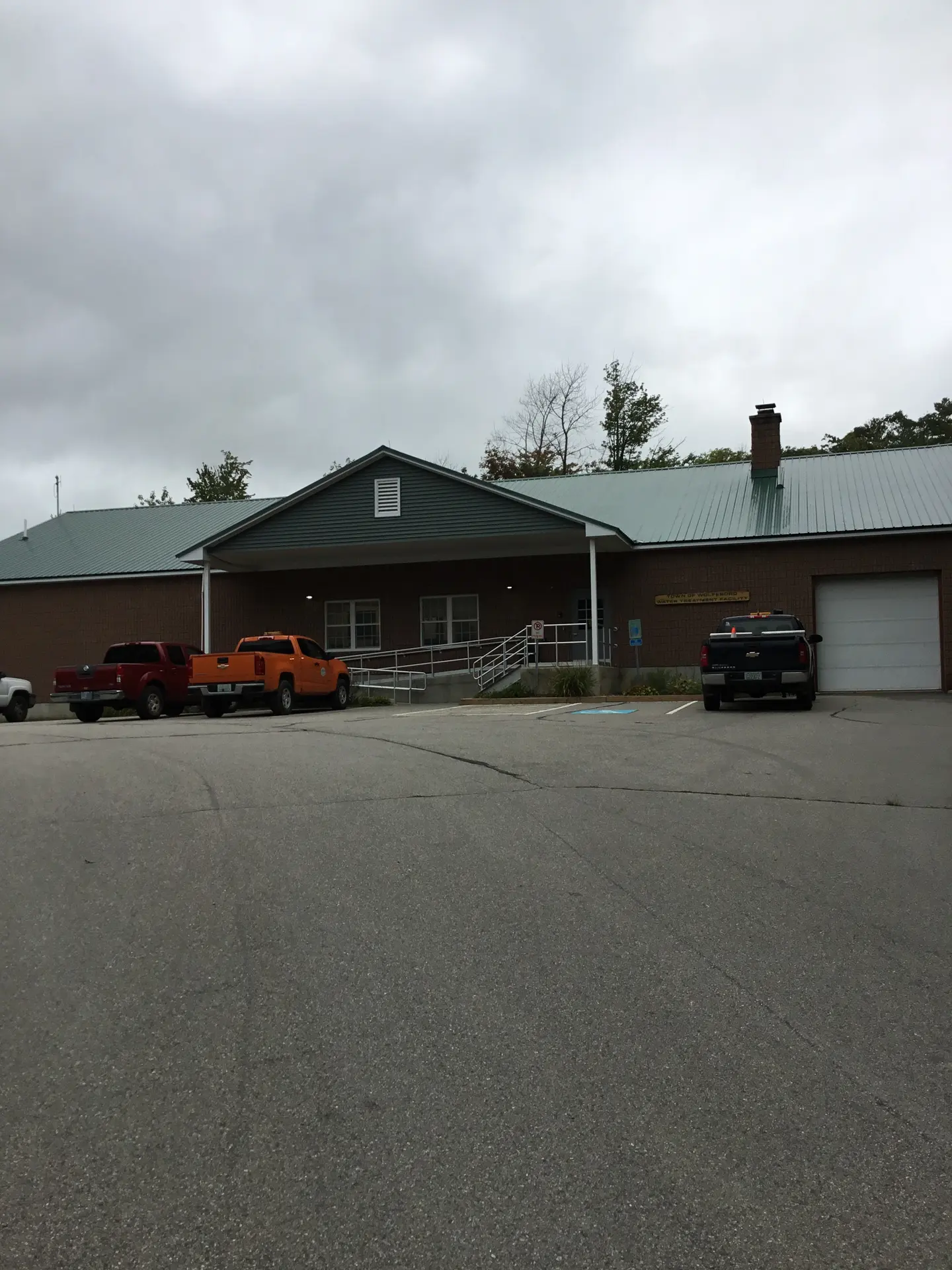 A single-story brown facility building with pickup trucks parked outside