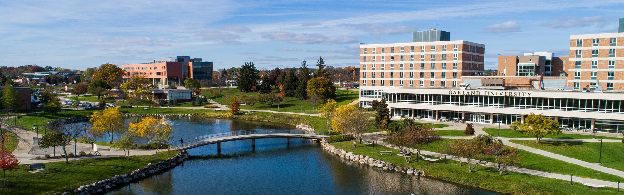 Oakland University campus with the reflecting pond, footbridge, and academic buildings in autumn