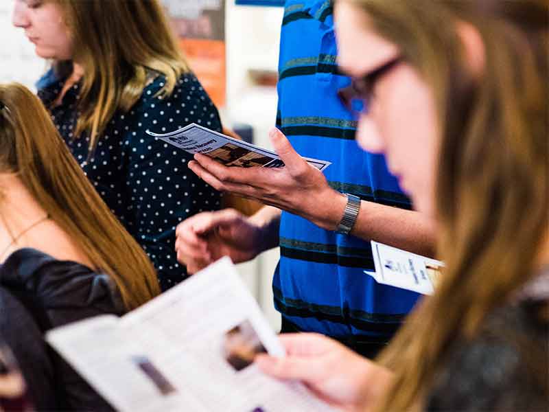 Oakland University students reading materials together at a research showcase