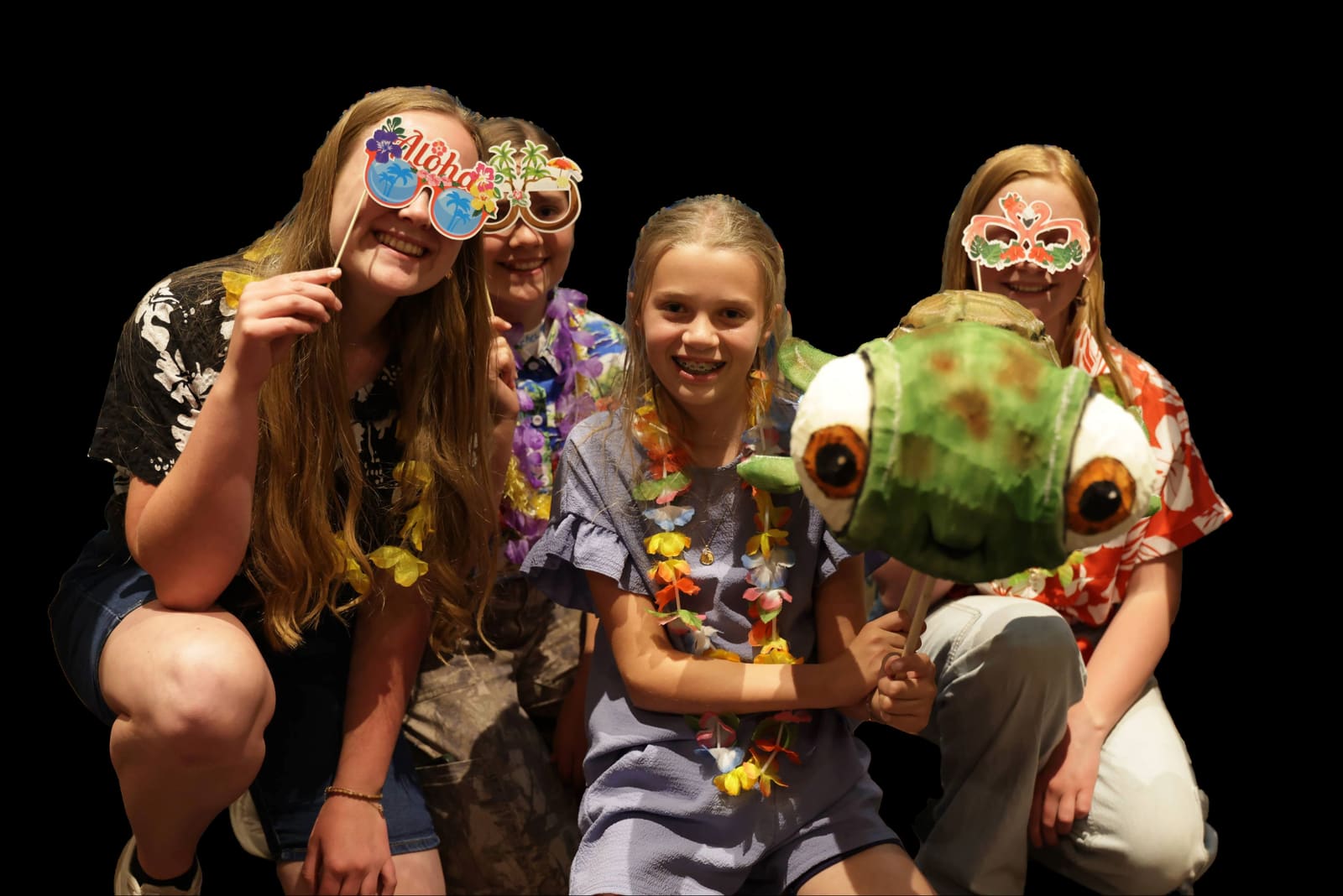 Kids in party masks and leis with a sea-turtle puppet at Lamp Post Creative Learning Center