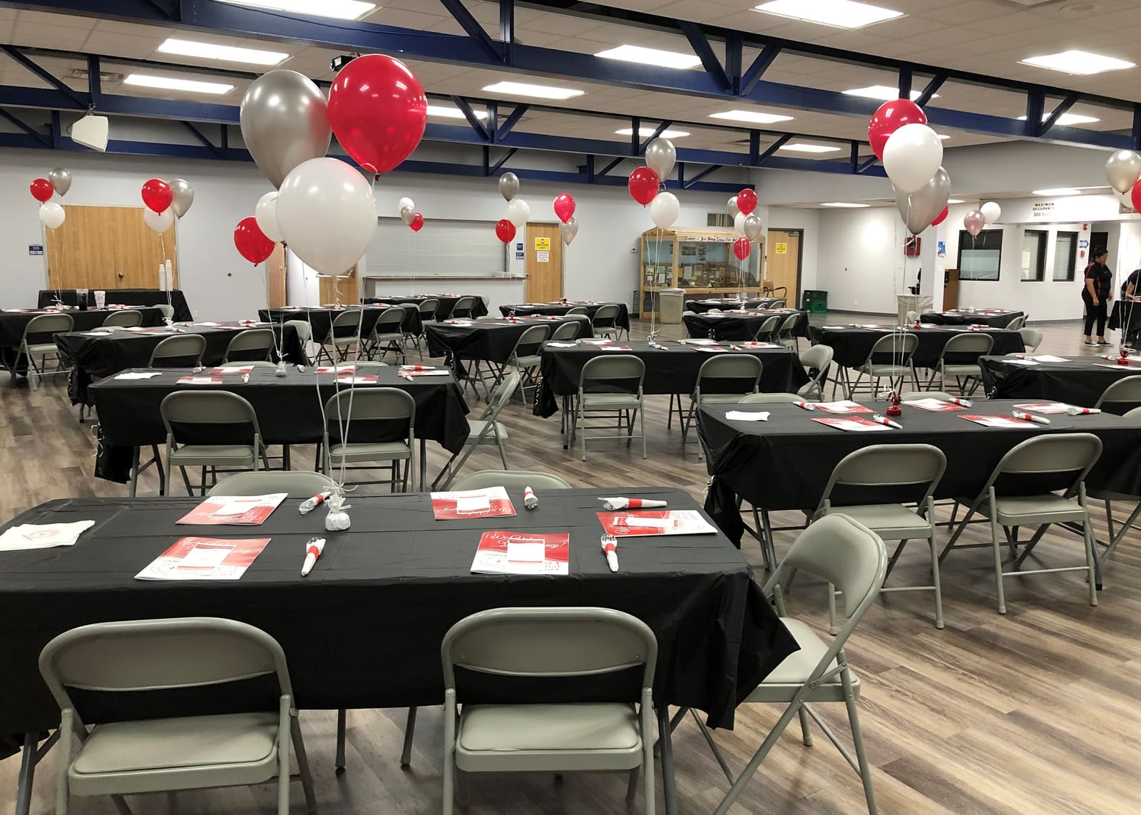 Luncheon tables set with black cloths and red programs under balloons