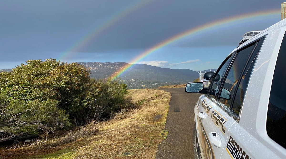 A double rainbow over the hills beside a Tribal Rangers patrol vehicle