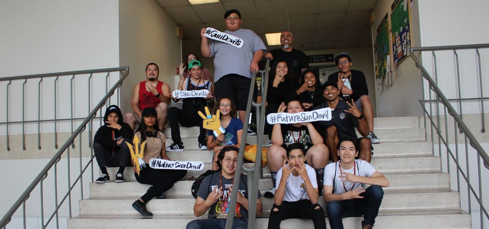 A group of young people posing on a staircase with handmade signs