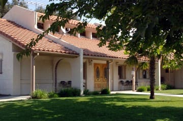 The Silver Feathers building, a tile-roofed hall behind a lawn and a young tree