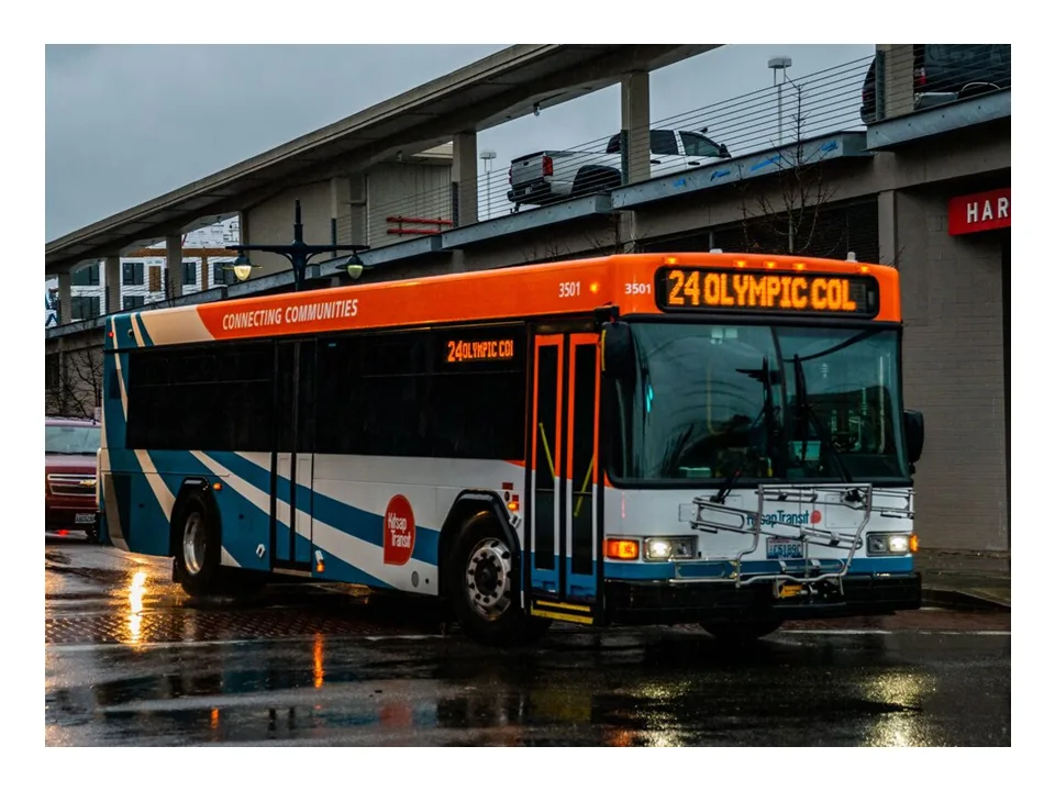 Kitsap Transit bus on Route 24 to Olympic College, on a wet street at dusk.
