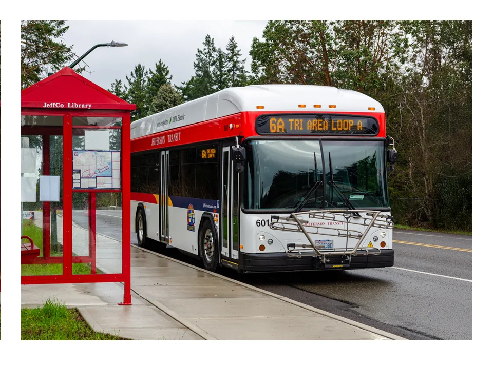 Jefferson Transit bus on Route 6A, Tri Area Loop, beside a red bus shelter.