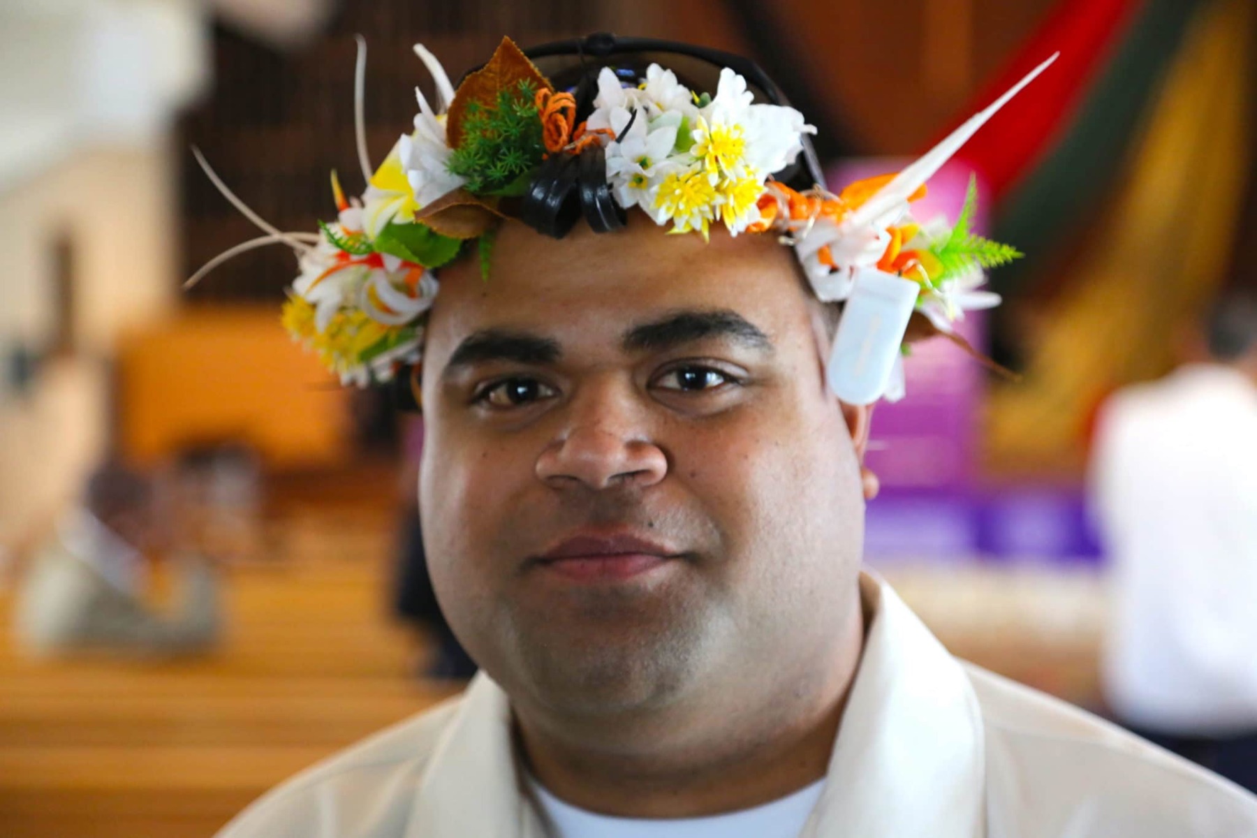 A smiling graduate wears a flower crown at commencement