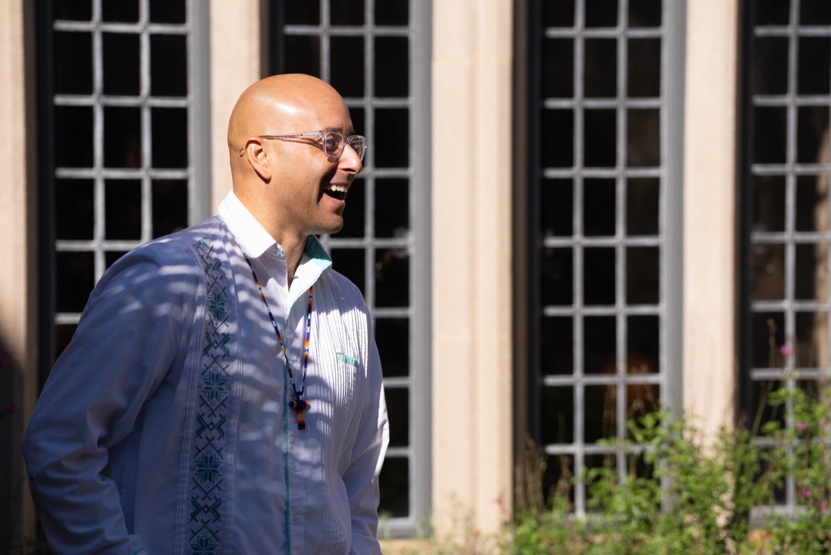 A PSR Collective instructor laughing in a sunlit campus courtyard lined with tall windows