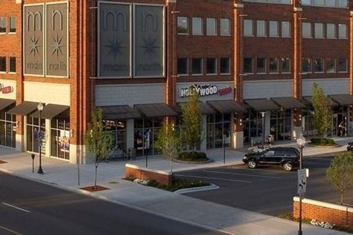Awninged shopfronts along the ground floor of the Main North block, with street trees and parked cars