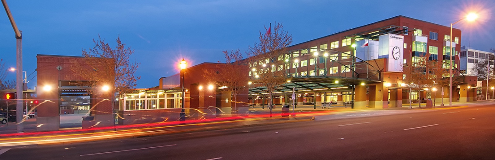Courthouse Square transit center at dusk, buses waiting in their bays under the station lights in downtown Salem