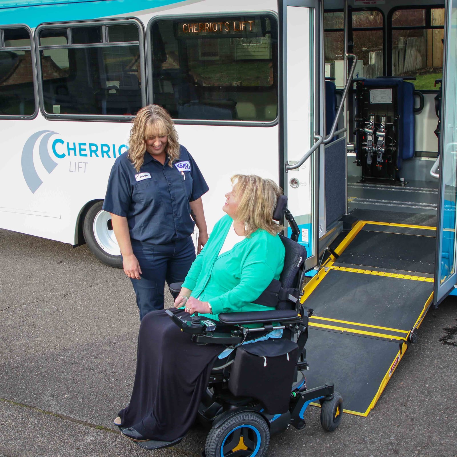A Cherriots operator meets a rider in a power wheelchair at the van’s ramp