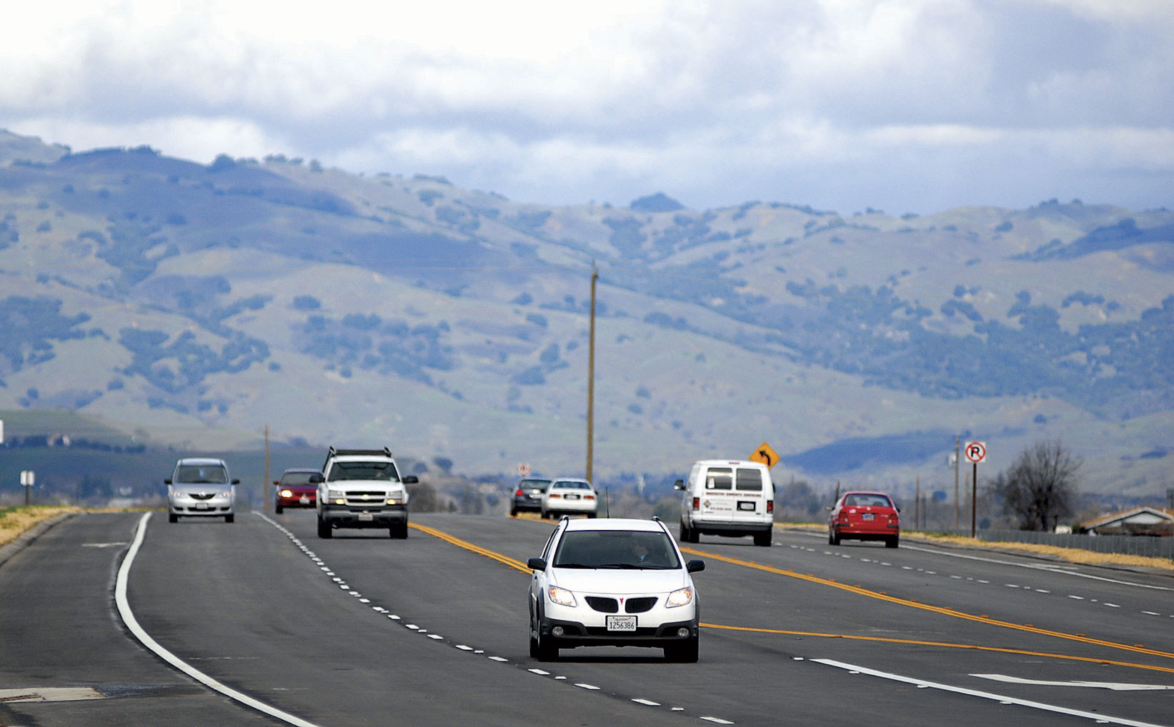 Traffic moving along the widened State Route 25 below the dry San Benito County hills