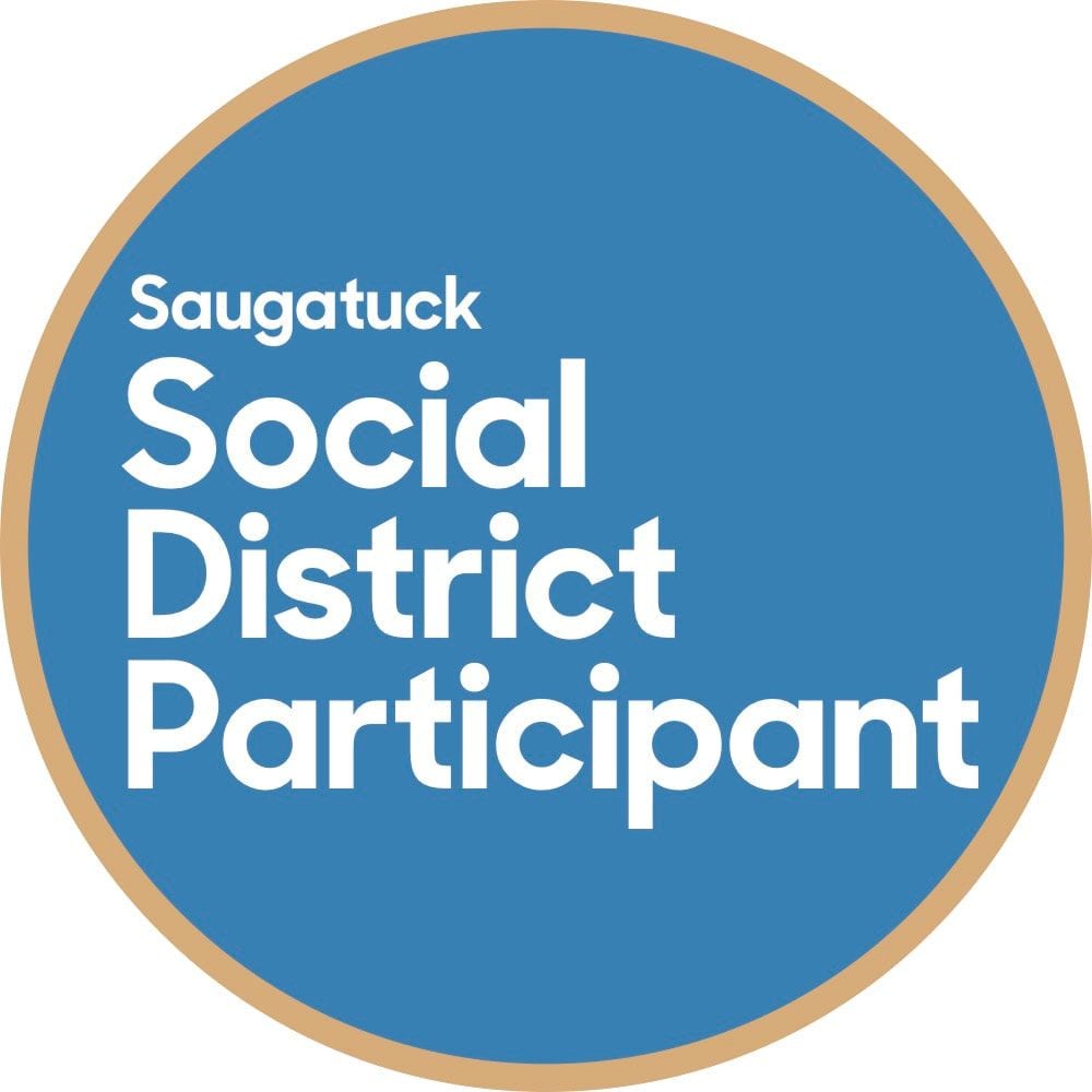 The round Saugatuck Social District Participant decal: white lettering on a blue circle with a tan rim.