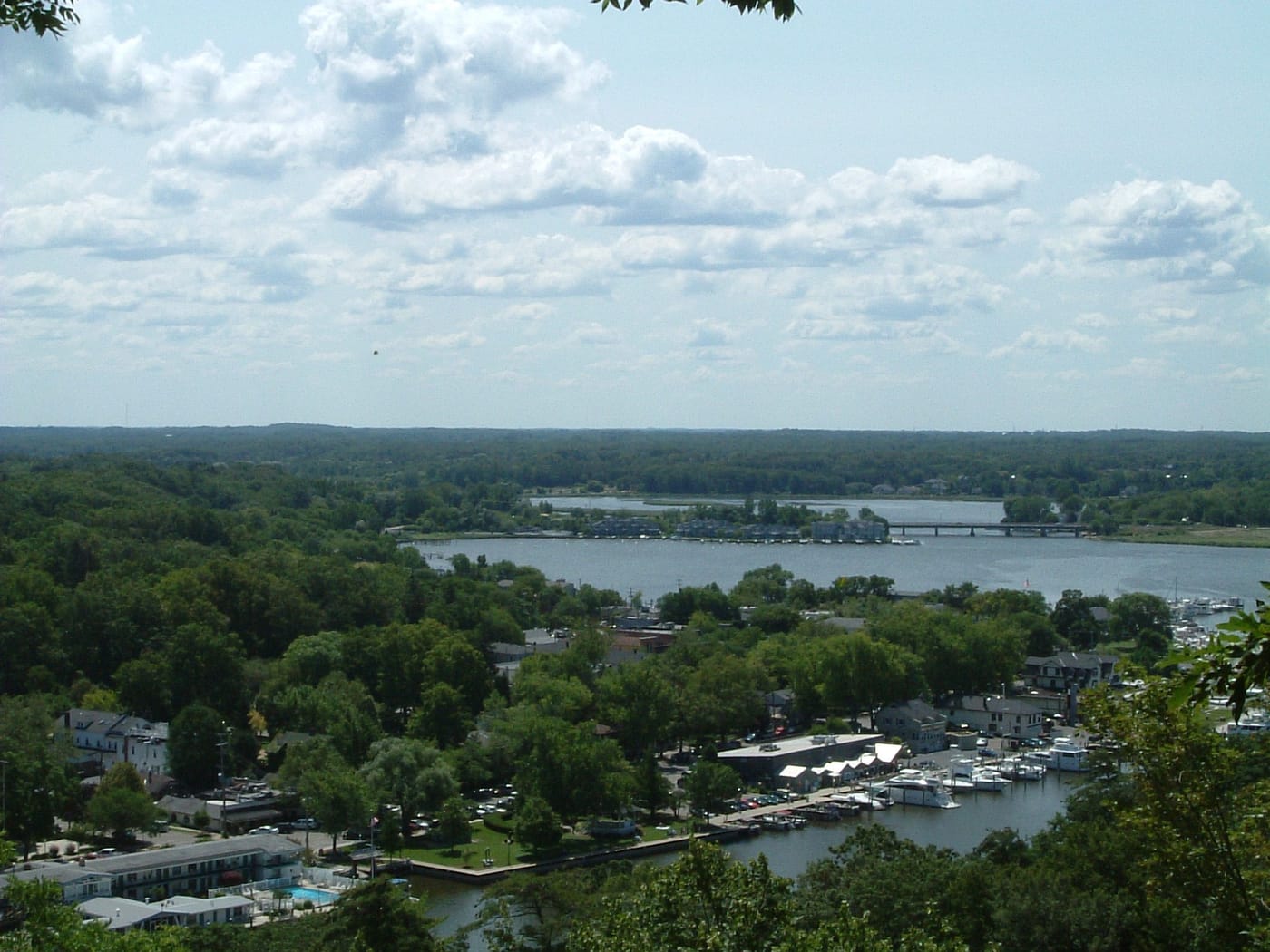 Looking down from Mt. Baldhead over treetops to the marina, downtown Saugatuck, and the Kalamazoo River winding inland.