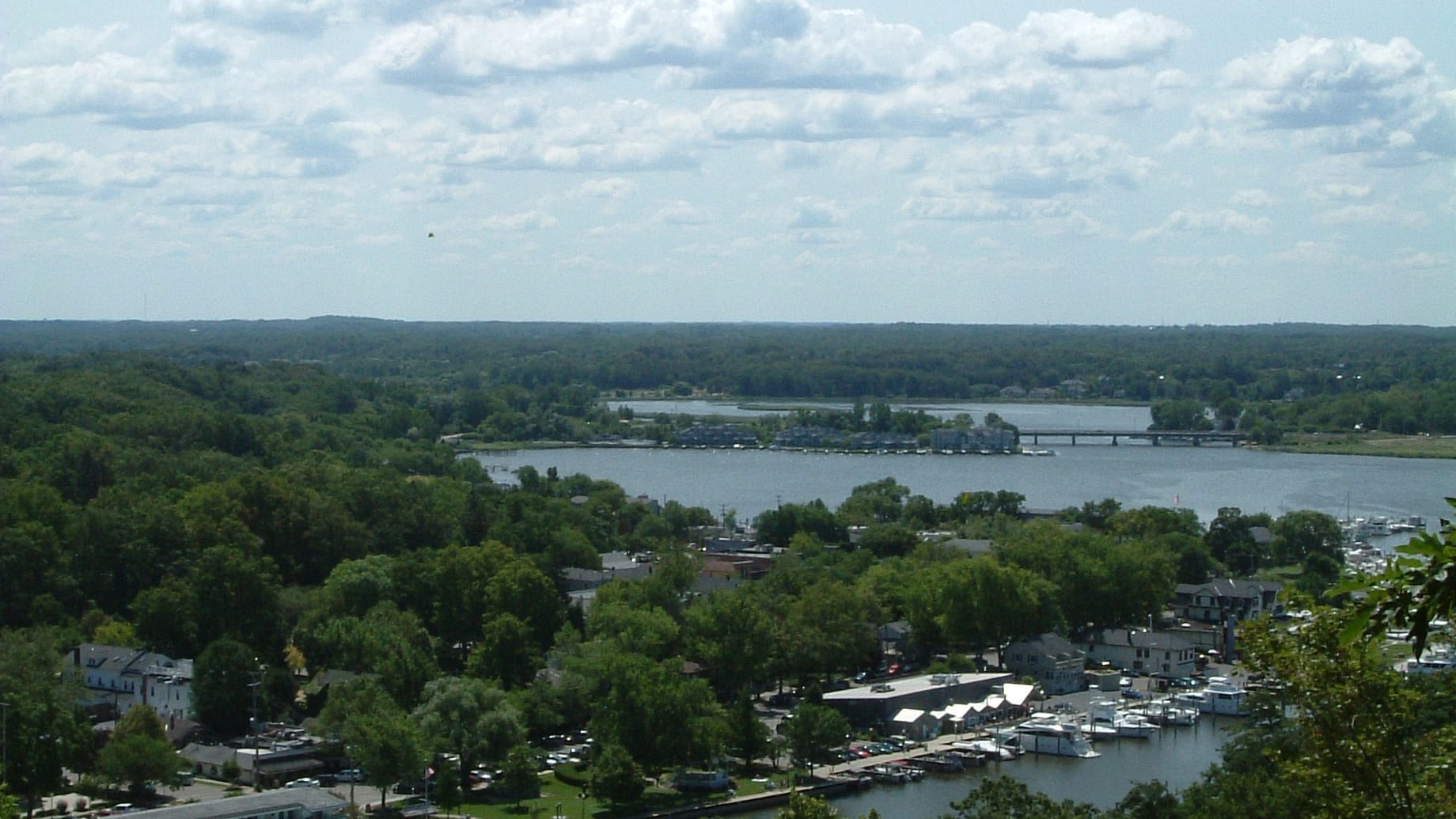 Looking down from Mt. Baldhead over treetops to the marina, downtown Saugatuck, and the Kalamazoo River winding inland.
