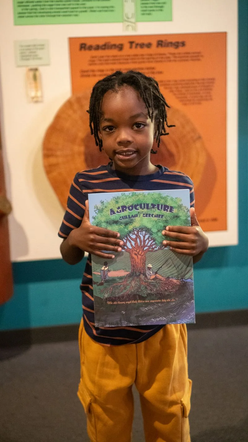 A child holds up a drawing at a reading activity.