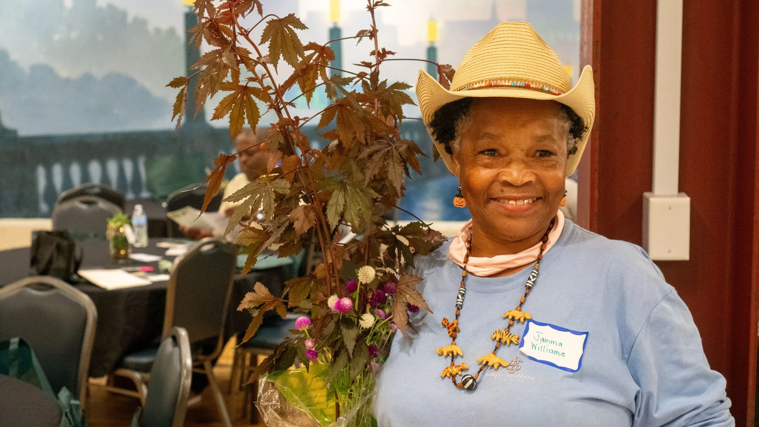 An event attendee smiles beside a plant display.
