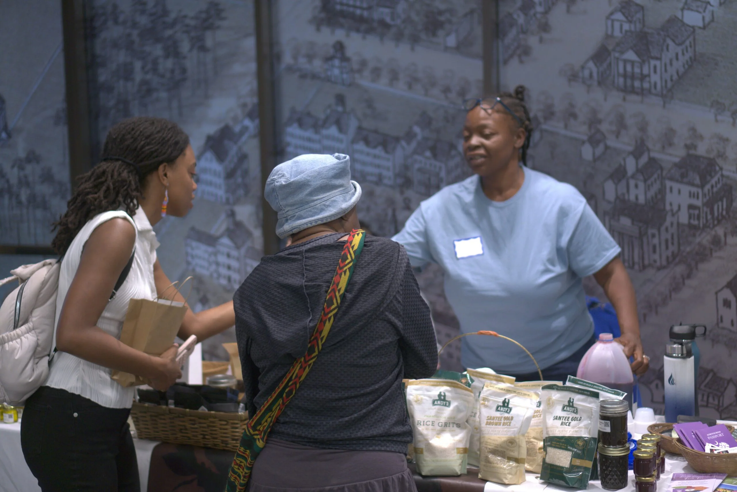 People talk at a vendor table during a community event.
