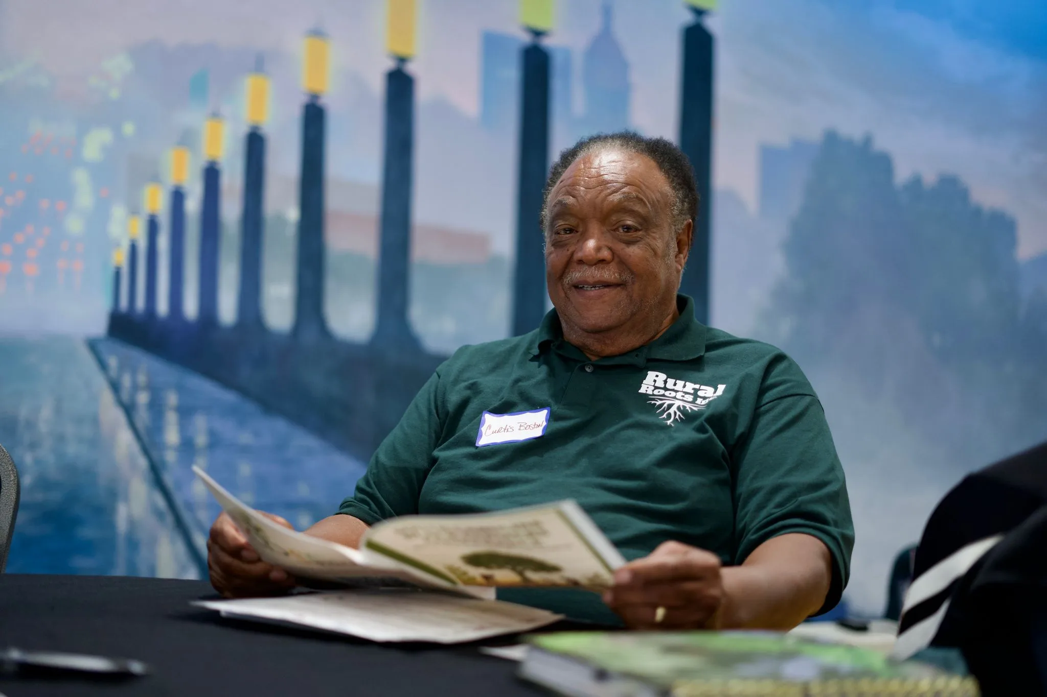 A farmer smiles while reading printed materials at a Coalition session table.