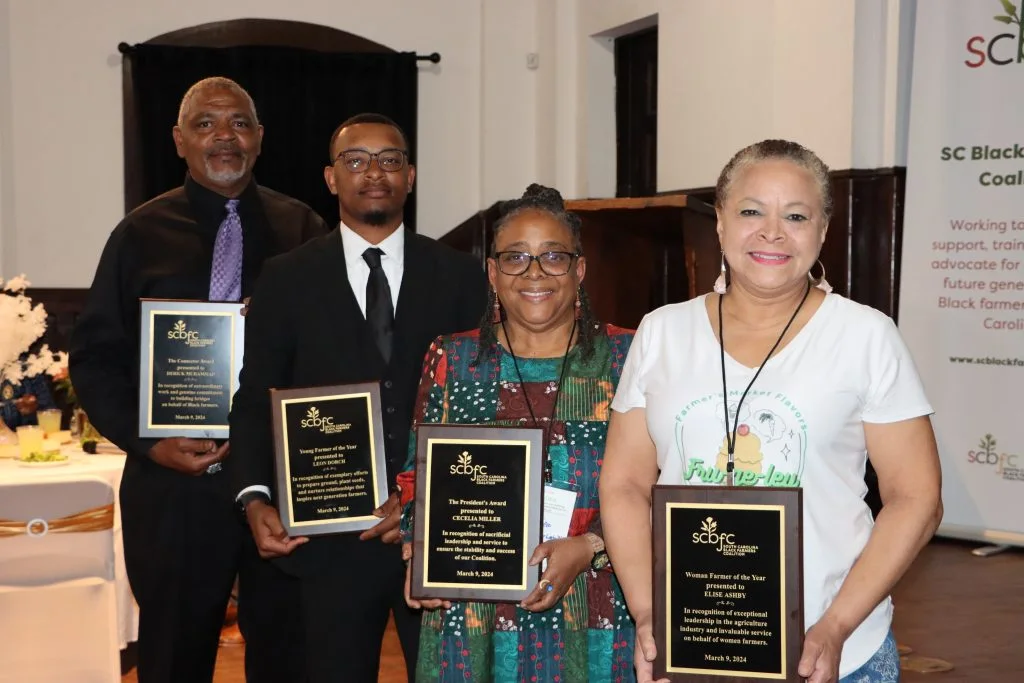 Four people hold awards at a South Carolina Black Farmers Coalition event.