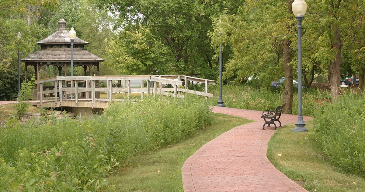 A brick path curving through prairie grasses to a wooden gazebo and boardwalk